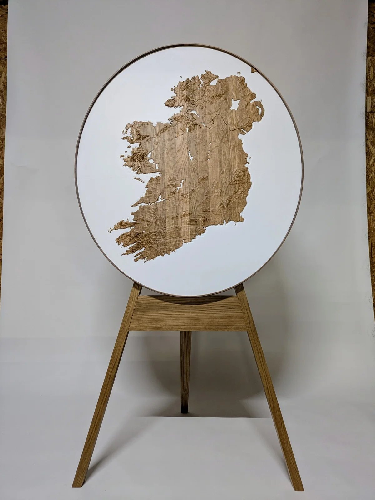 Framed elliptical oak model of Ireland on a white backing, displayed on an easel