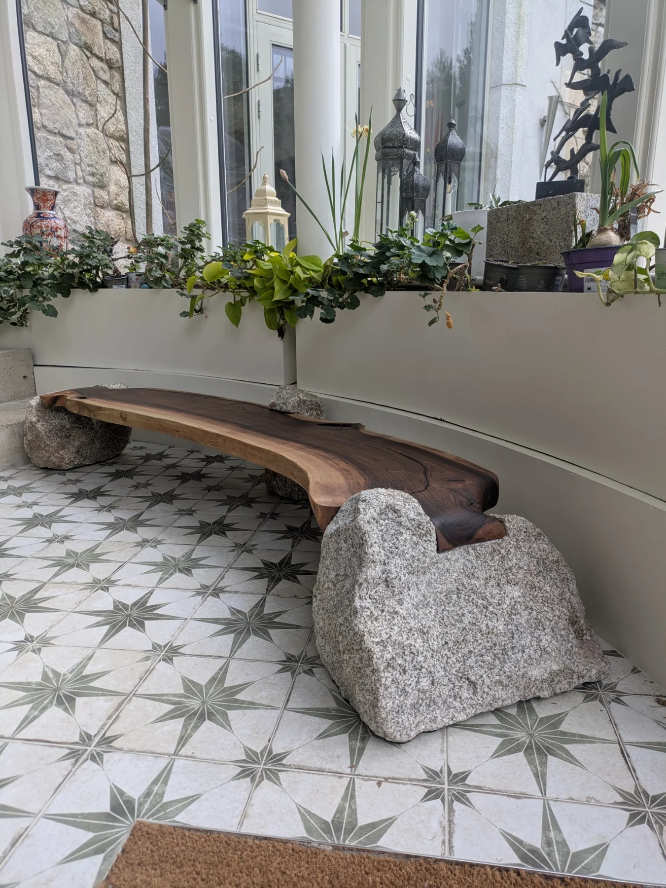 The granite and walnut bench beside a window in a planted interior