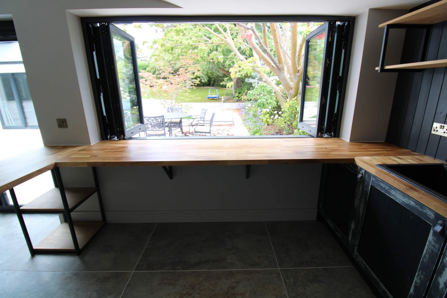 The oak bar worktop aligned with the open windows overlooking the garden