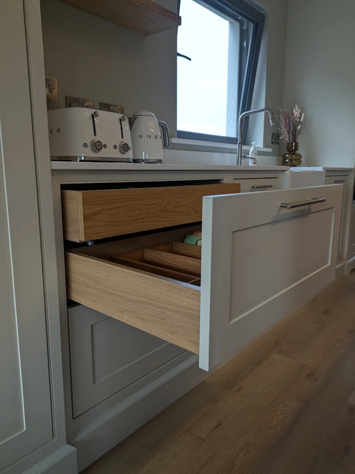 An inner oak drawer concealed above a deeper divided drawer behind a single painted front