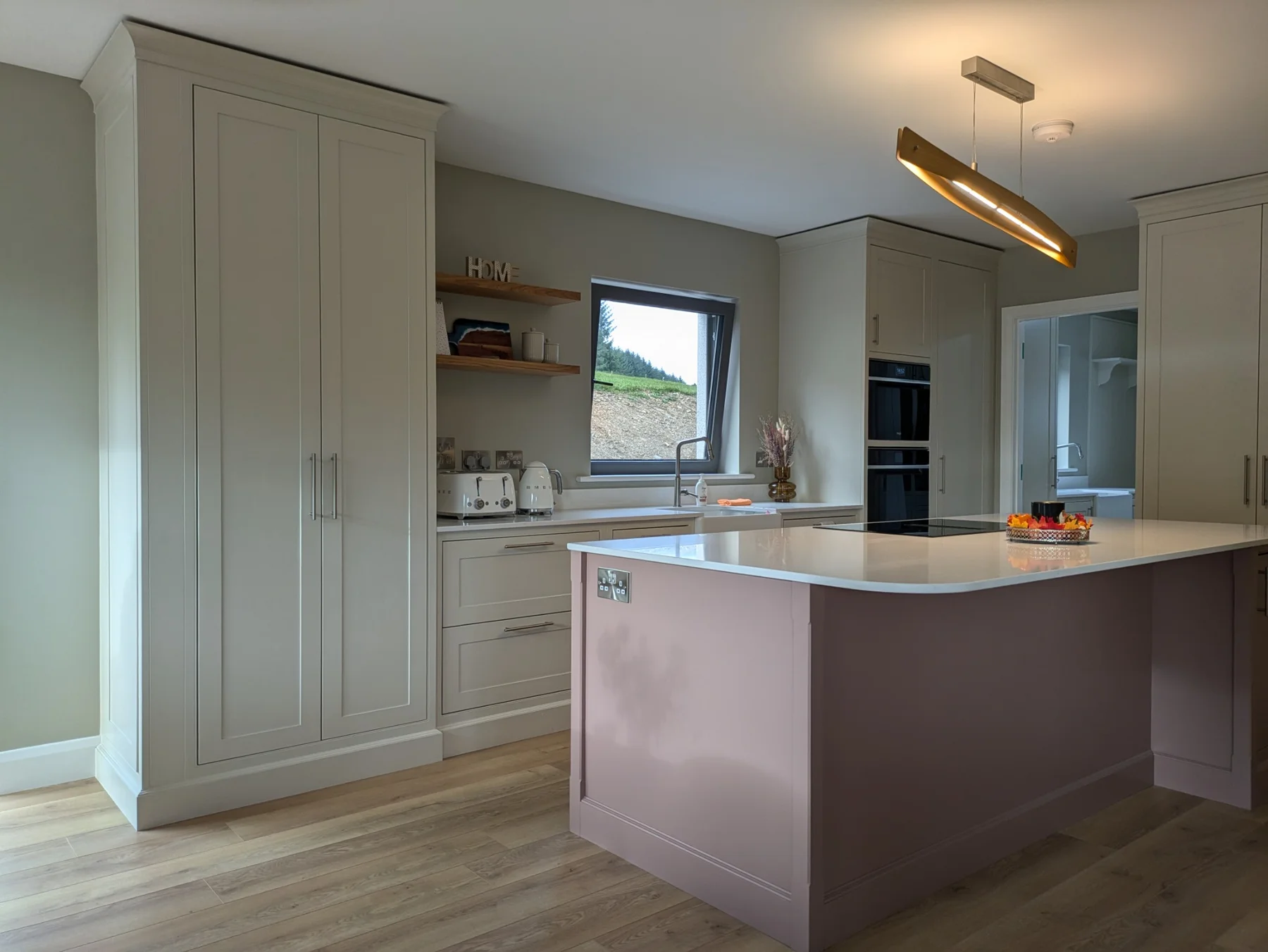 A traditional in-frame kitchen with a painted island, tall cupboards and cornice