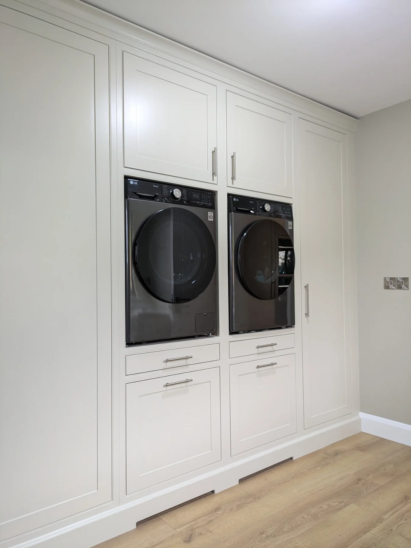 Matching painted utility cabinetry with raised laundry appliances and storage
