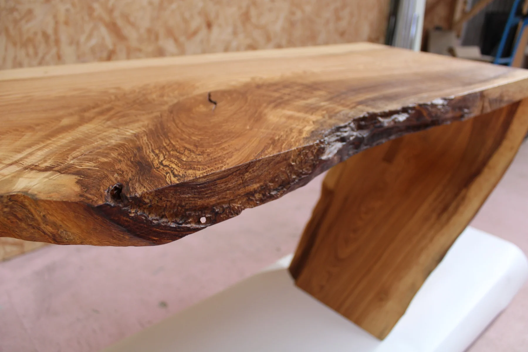 The grain and natural edge of the oak desk top above the curved support