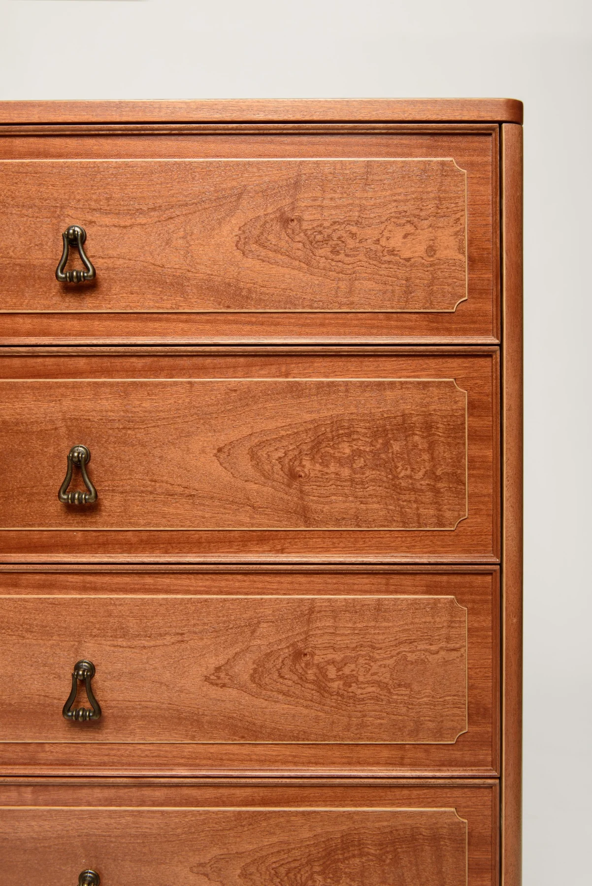 Mahogany veneer drawer fronts with oak inlay borders and drop handles