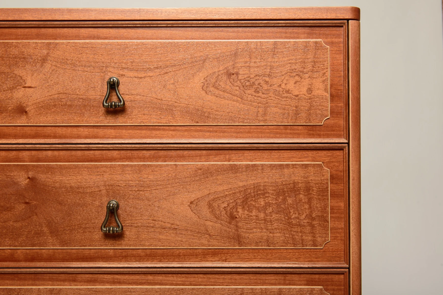 Close view of the figured mahogany veneer and oak inlay on the drawer fronts
