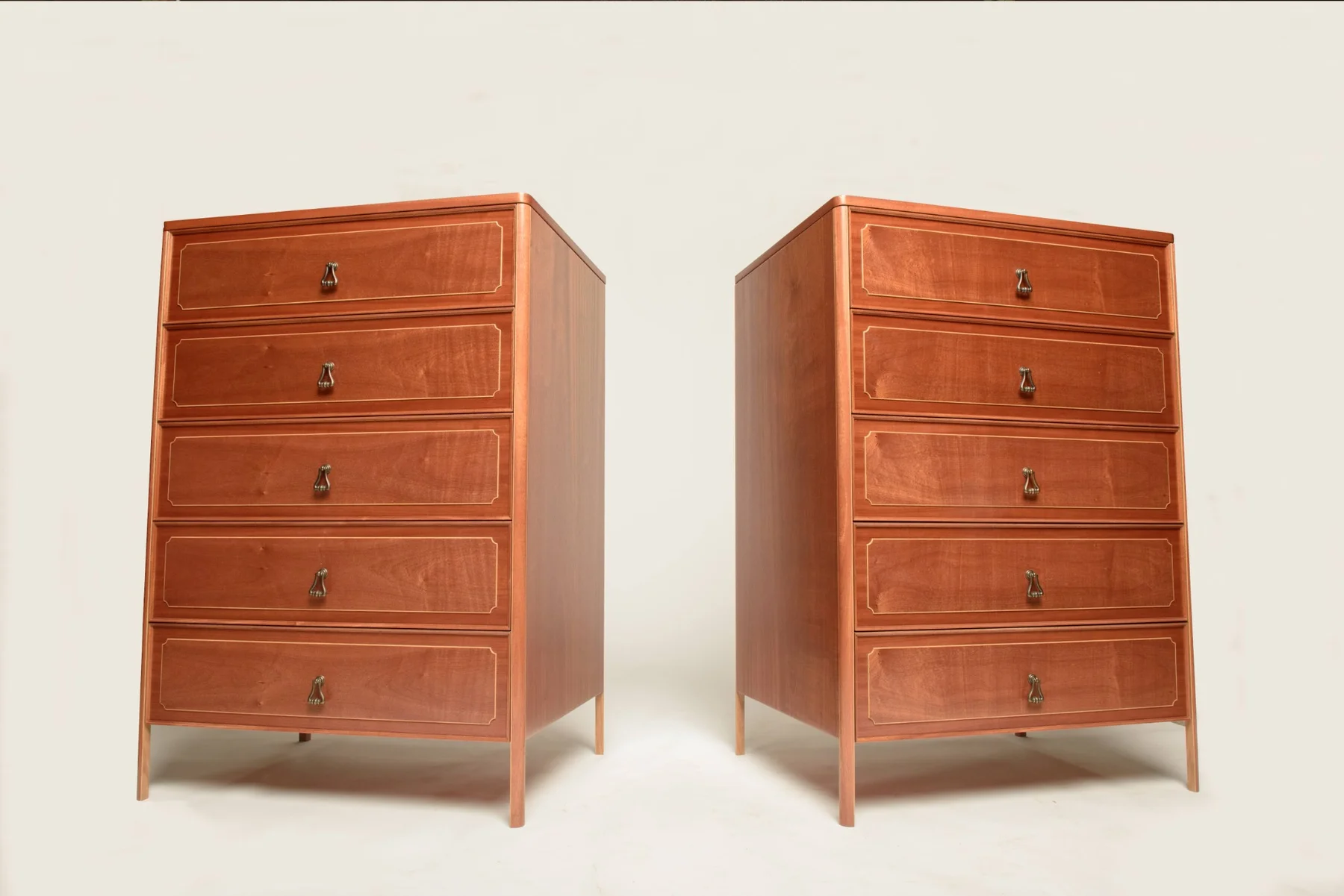 A pair of mahogany drawer dressers with slender Sapele legs and oak inlay around the drawer fronts