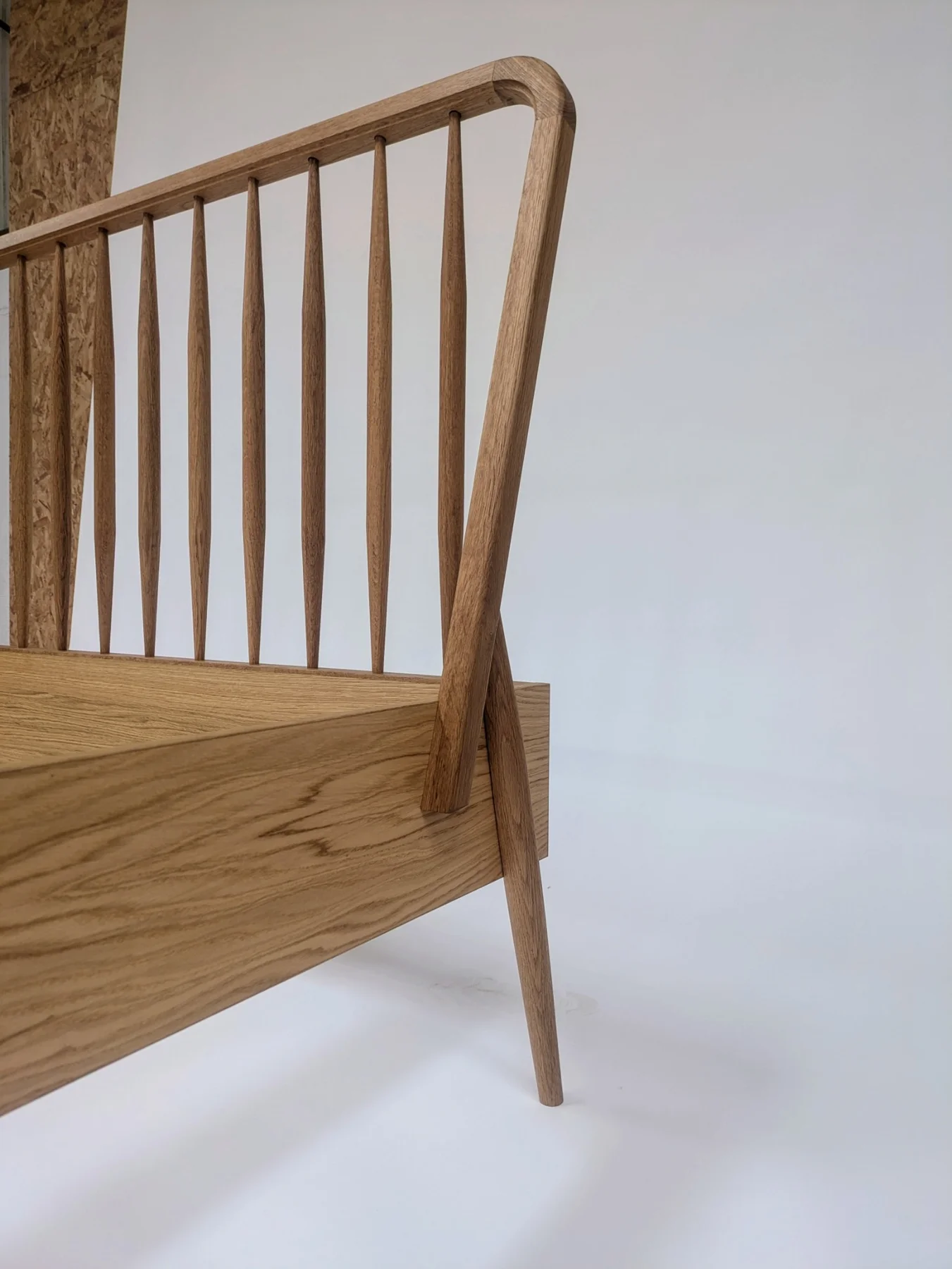 The rounded top rail and spindle headboard of the oak bed