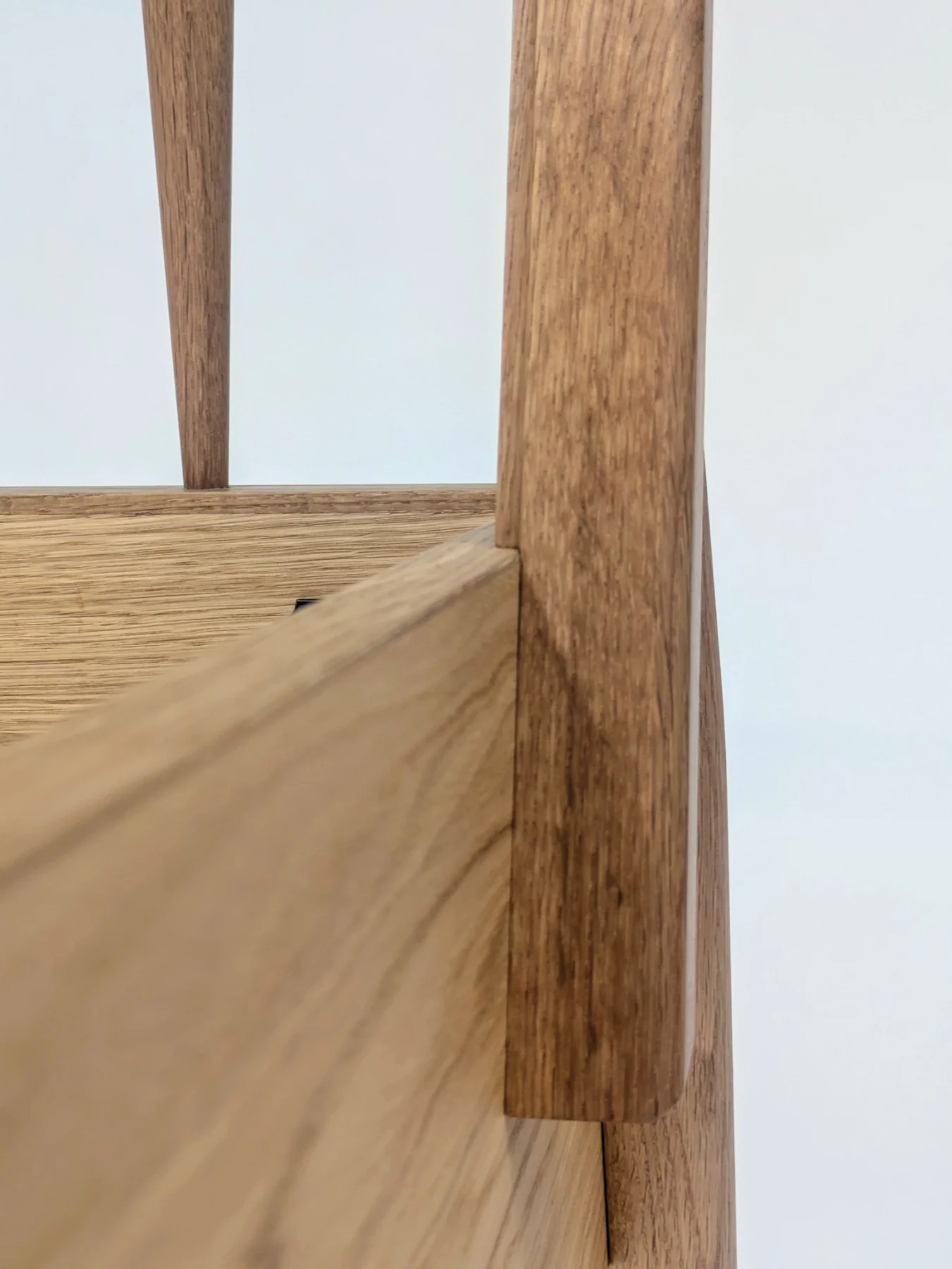 Close view of the oak bed rail meeting a tapered headboard post