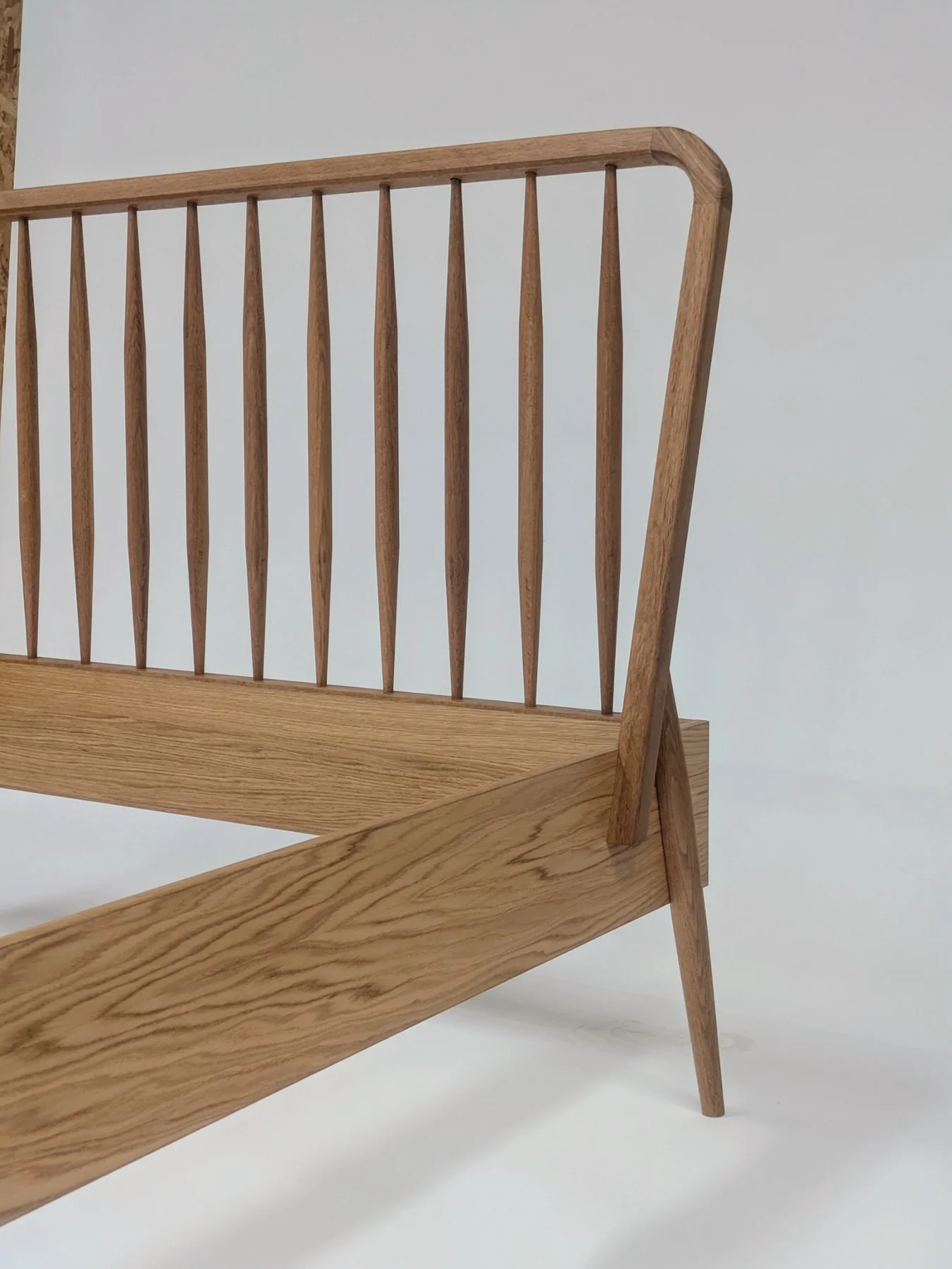 Oak spindles and the curved corner of the bed headboard
