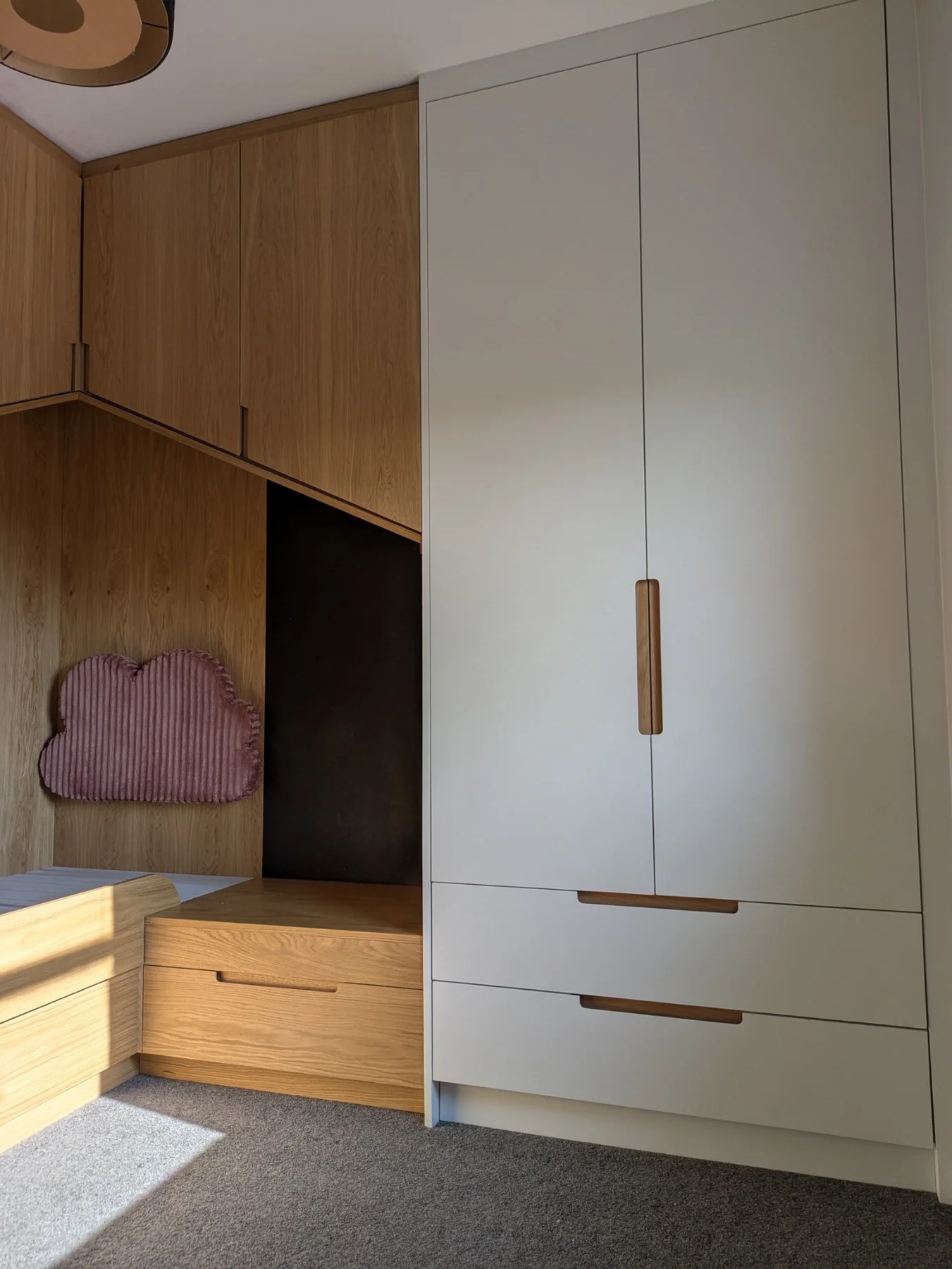 Painted wardrobe doors and lower drawers beside the oak bed