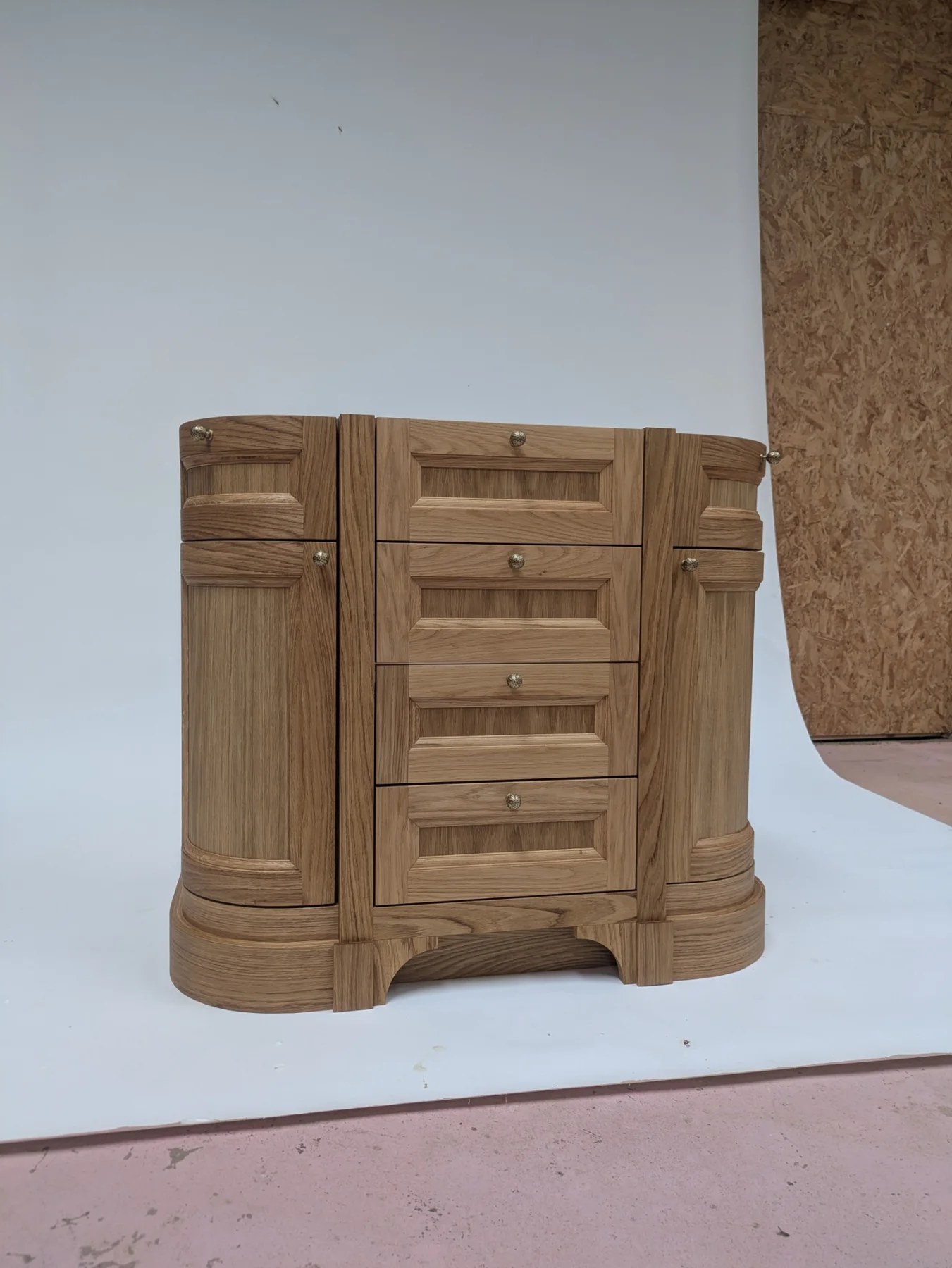 The oak vanity seen at an angle, showing the rounded fronts and panelled sides
