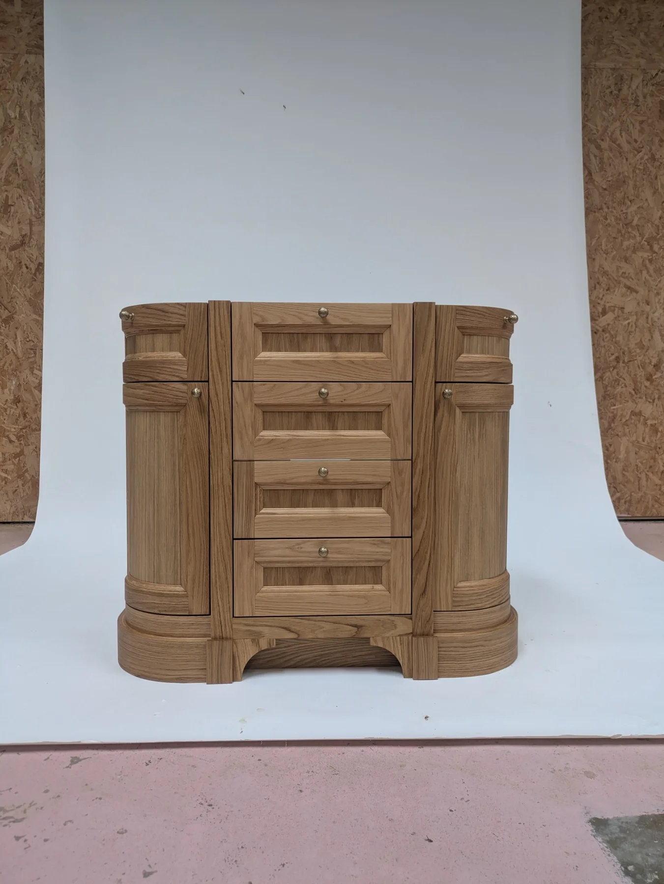 Oak bathroom vanity with curved end cupboards and a central bank of drawers