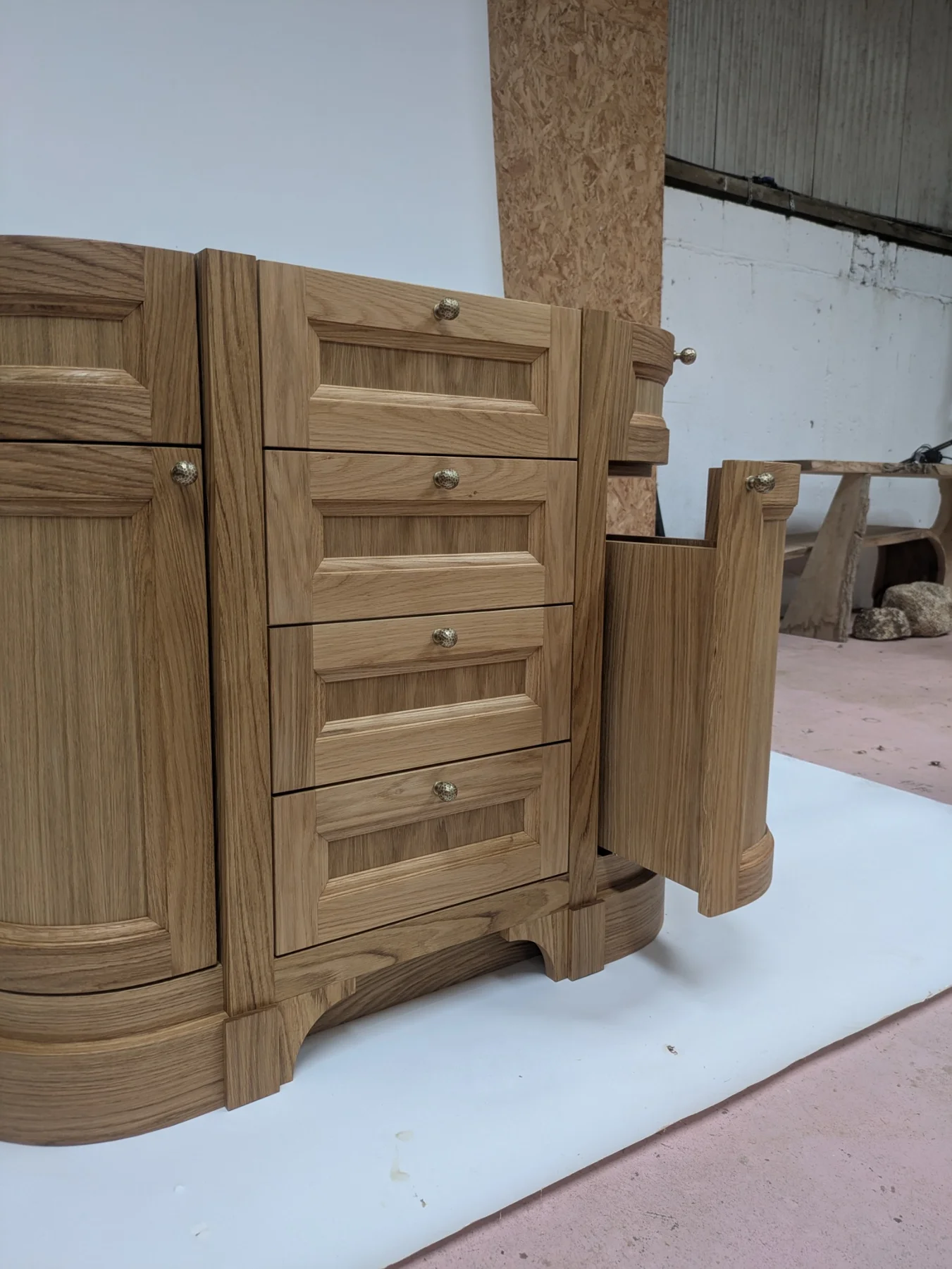 An open curved cupboard at the side of the oak bathroom vanity
