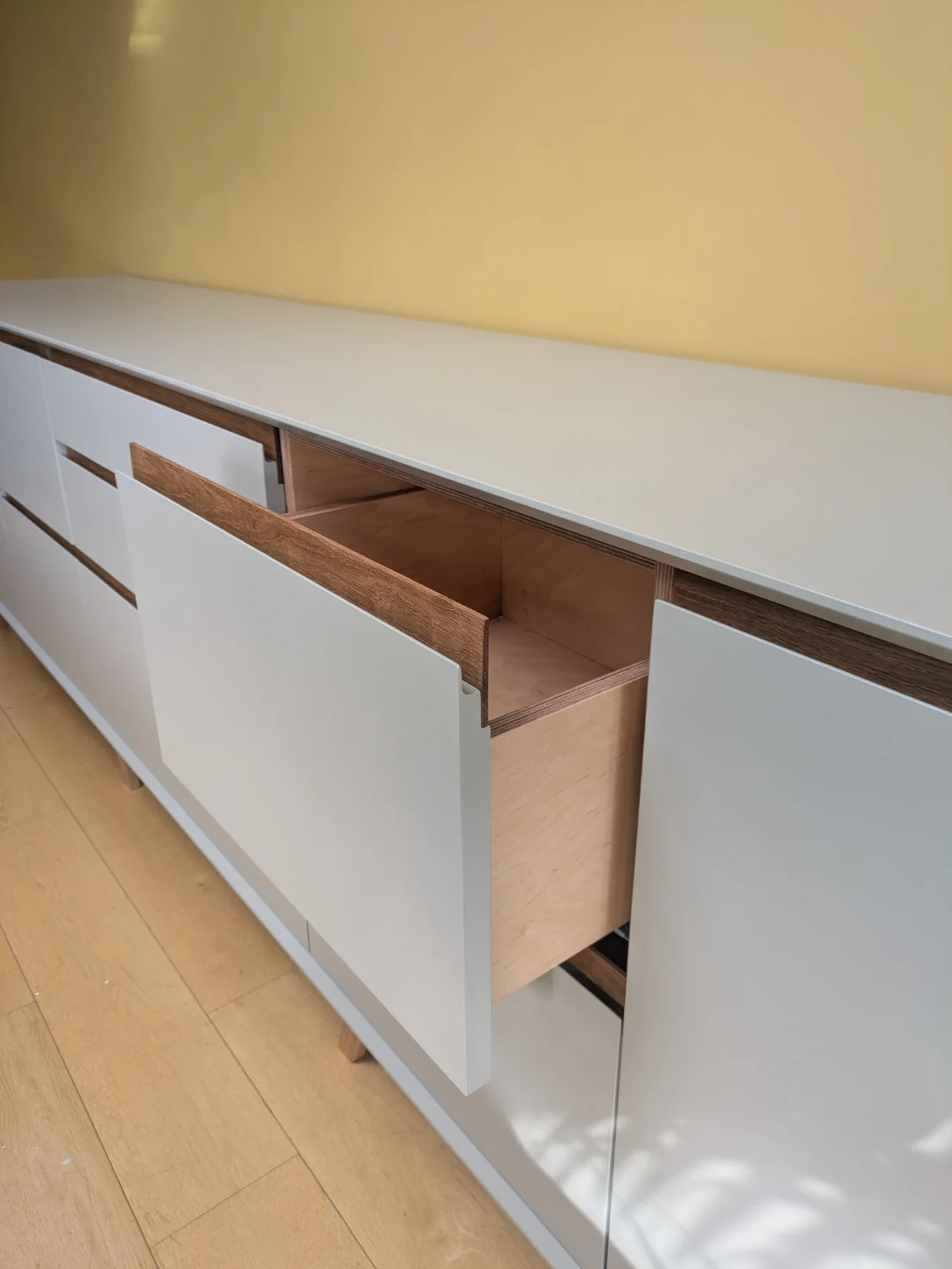 An open drawer showing the birch plywood interior behind a hand-painted front