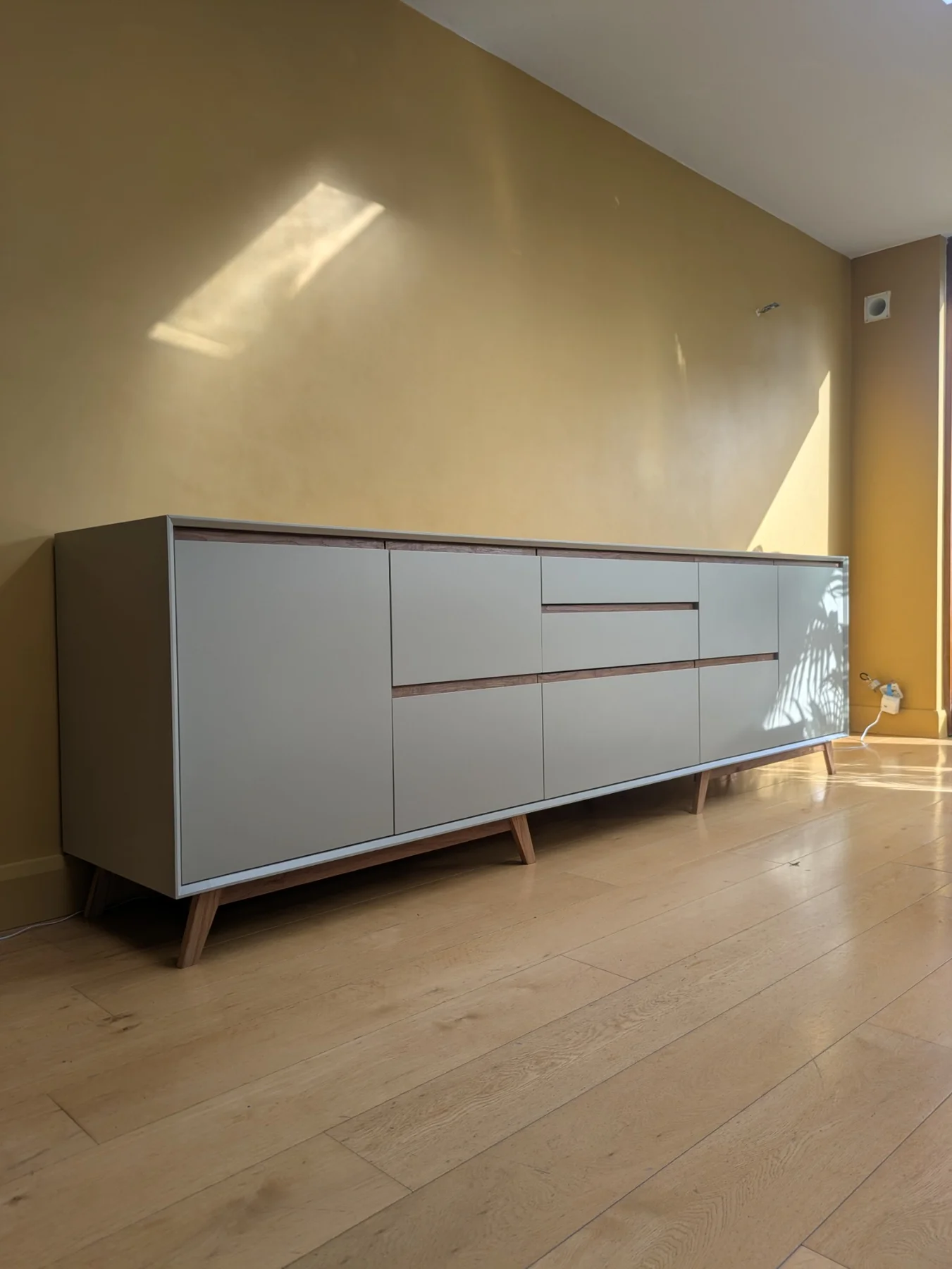 A painted sideboard with oak reveals and solid oak legs against a warm yellow wall