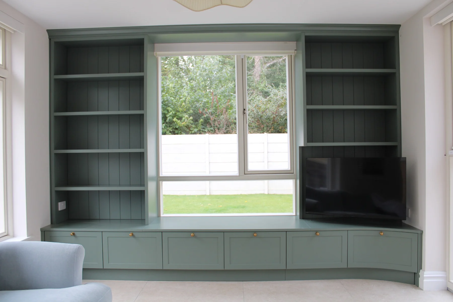 Painted bookshelves and a TV unit framing a kitchen-area window