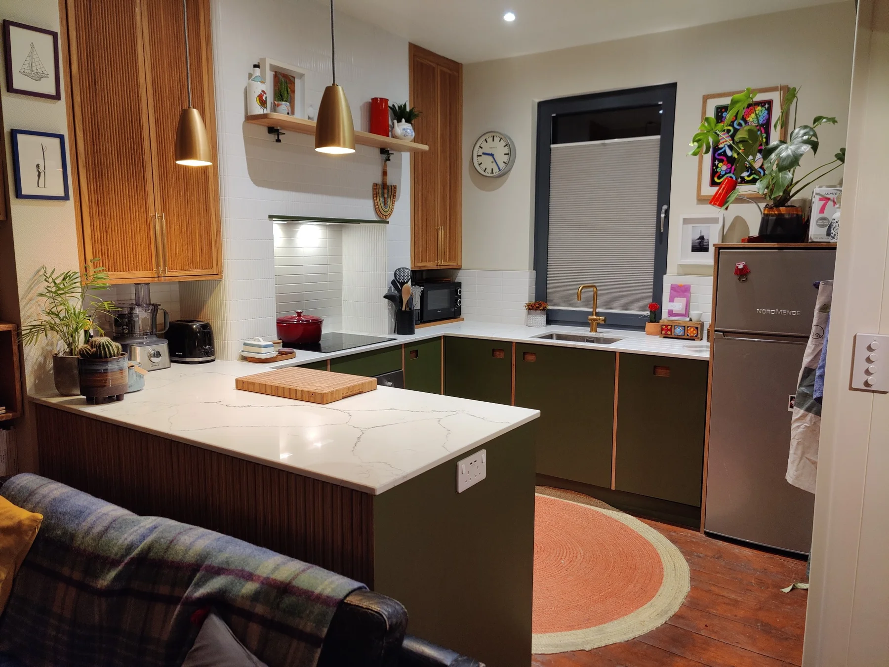 A kitchen combining painted fronts, reeded oak wall cupboards and a peninsula