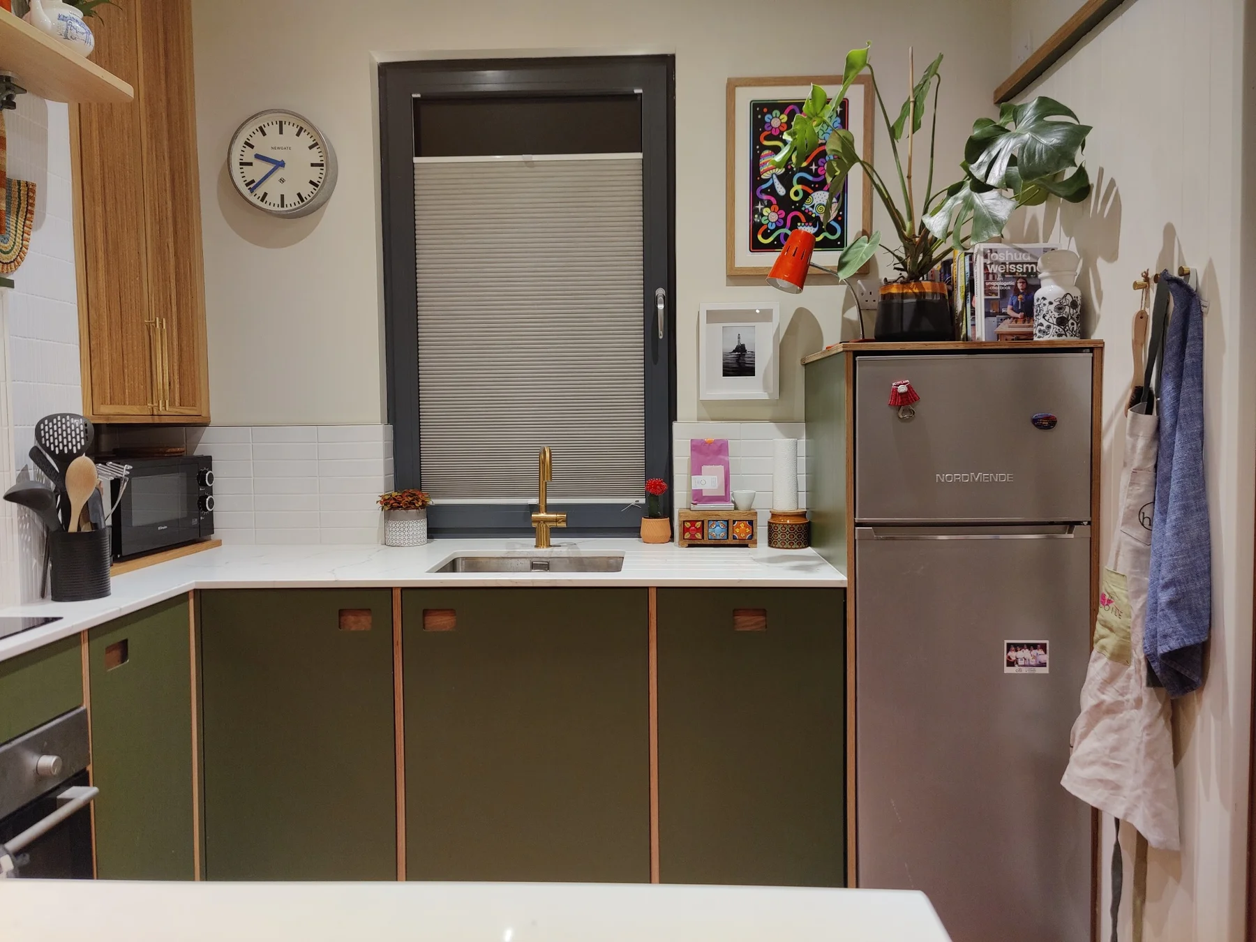 Painted kitchen fronts with brass handle details beneath the window