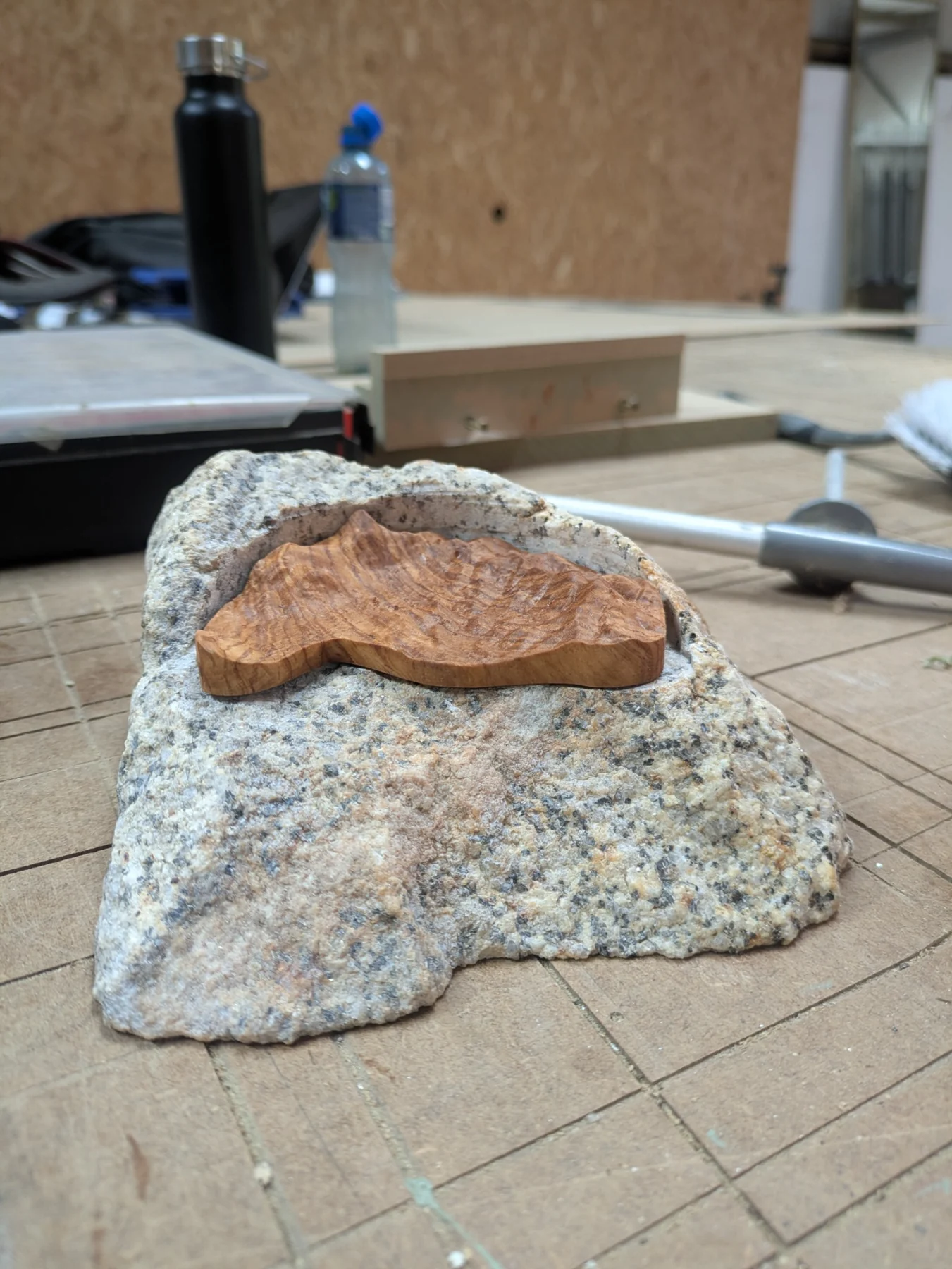 A small wooden terrain relief fitted into a piece of granite on the workshop bench