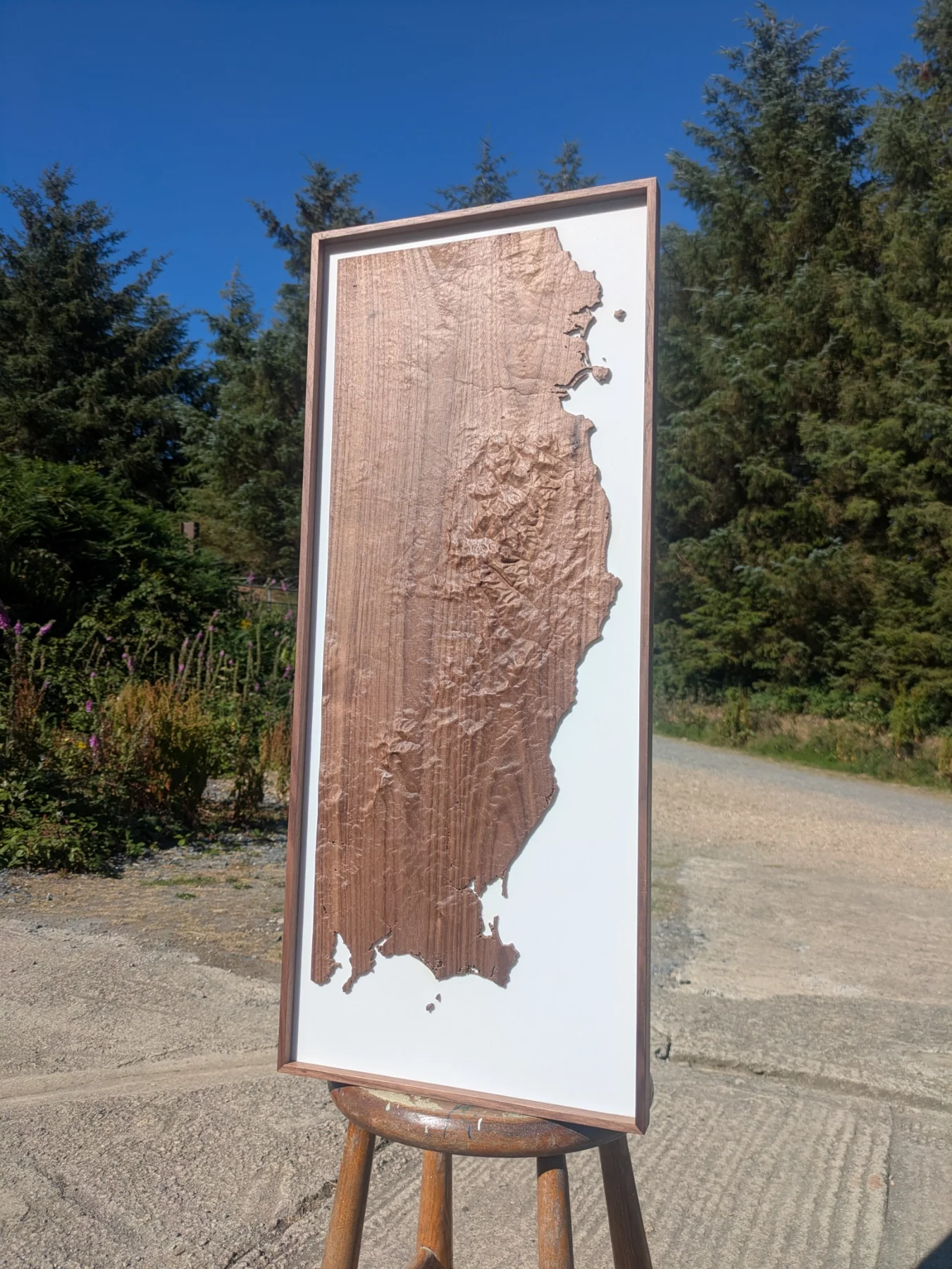 A tall framed terrain model displayed outdoors on an easel