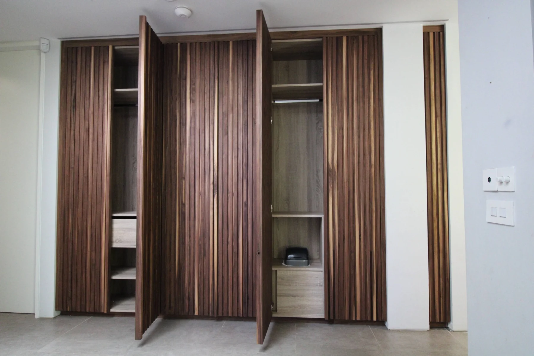 Hallway cabinets open to show Cambrian Oak shelves, drawers and hanging space