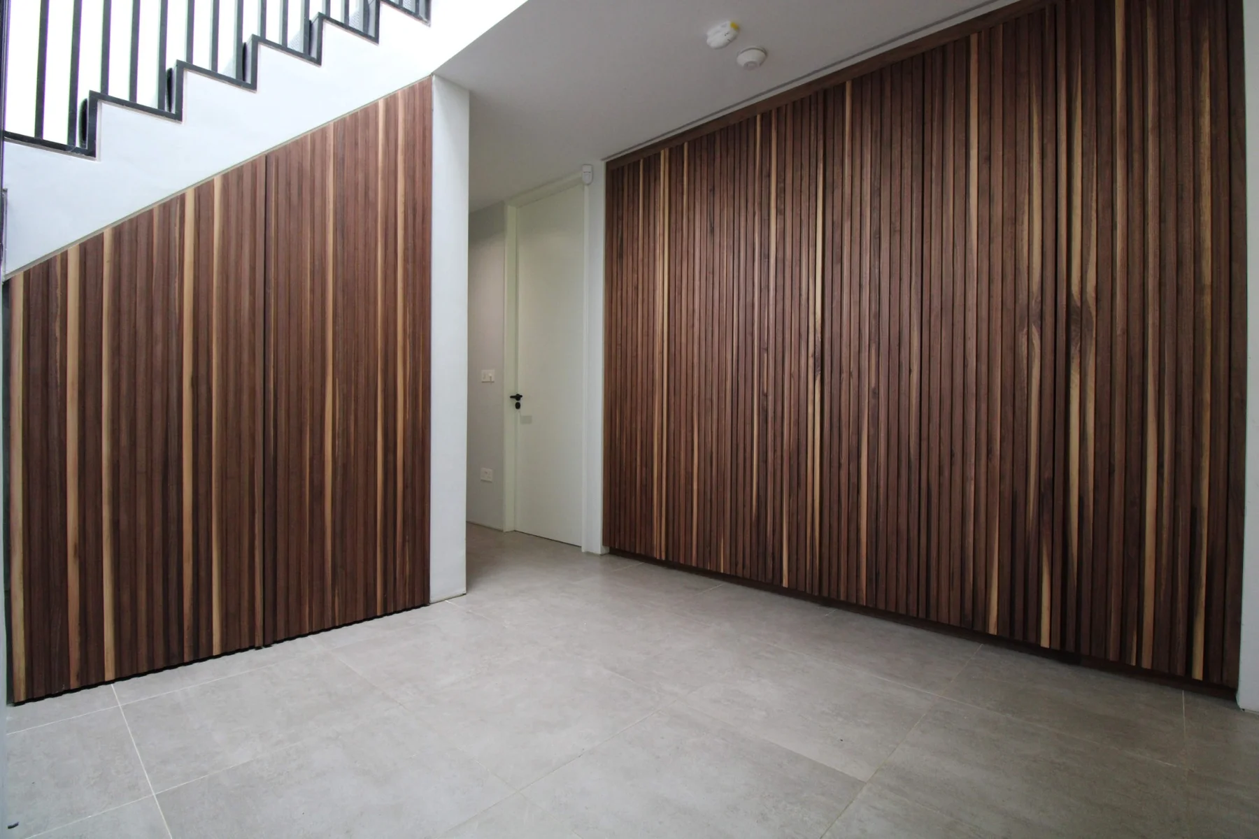Walnut slatted hallway storage doors alongside matching panels beneath the staircase
