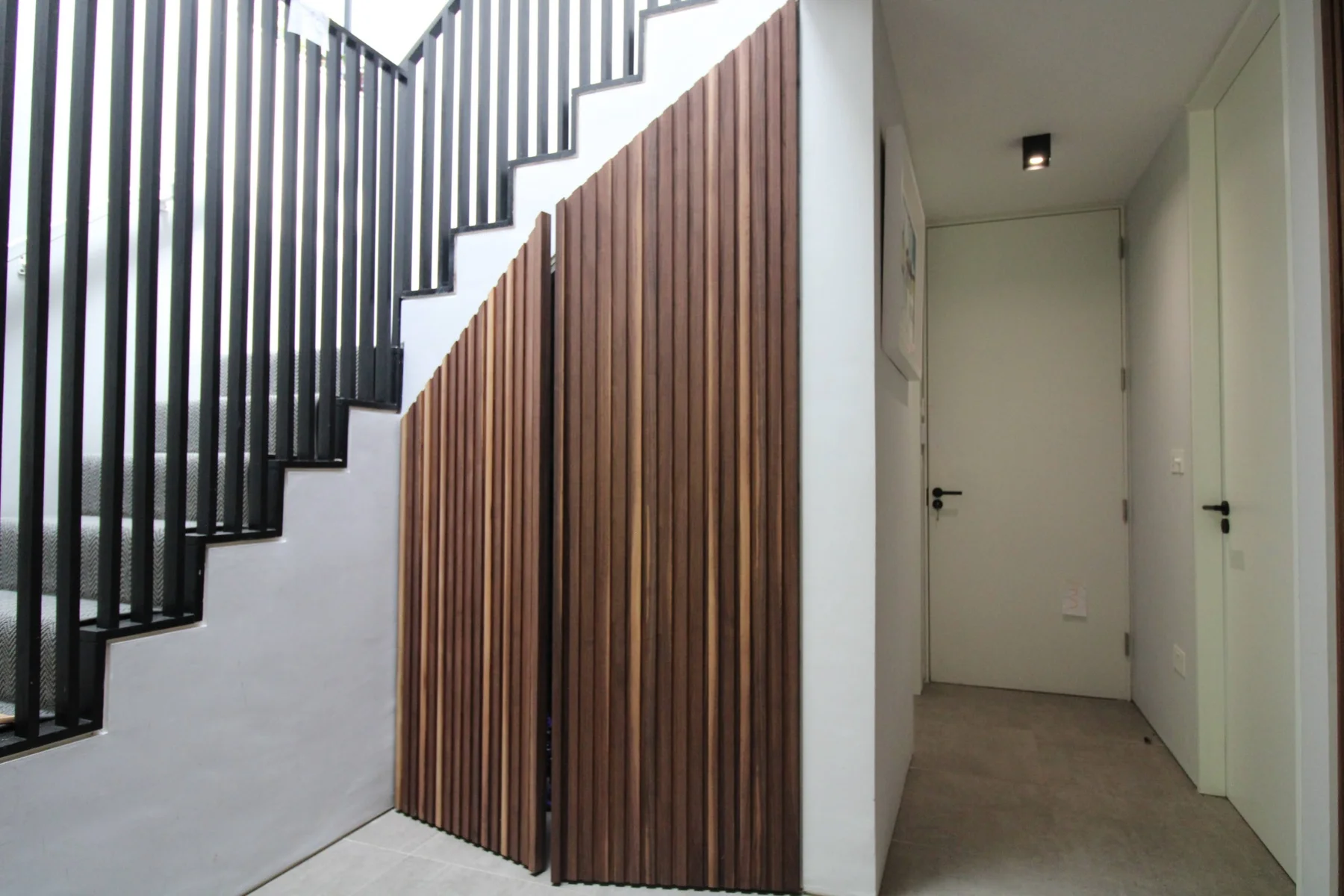 Walnut slatted panels following the slope beneath the staircase